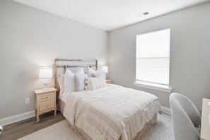 A bedroom with a bed, nightstands, a lamp, a chair, and a window. - New 3BR Home - Walk to Downtown Belmont - Near CLT - Sleeps 8 (Belmont)