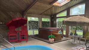 Una piscina interna con idromassaggio, sedie rosse e un'area bar.