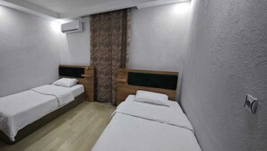 A small, clean room with two single beds, a wooden headboard, a wall-mounted air conditioner, and a curtain. - BEYSEHİR APART OTEL (Beysehir)
