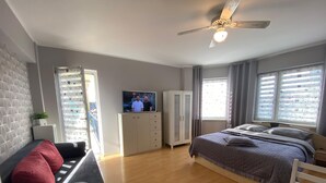 A modern bedroom with a bed, a sofa, a TV, and a wardrobe. - Apartment Close to the Beach, Miedzyzdroje (Międzyzdroje)