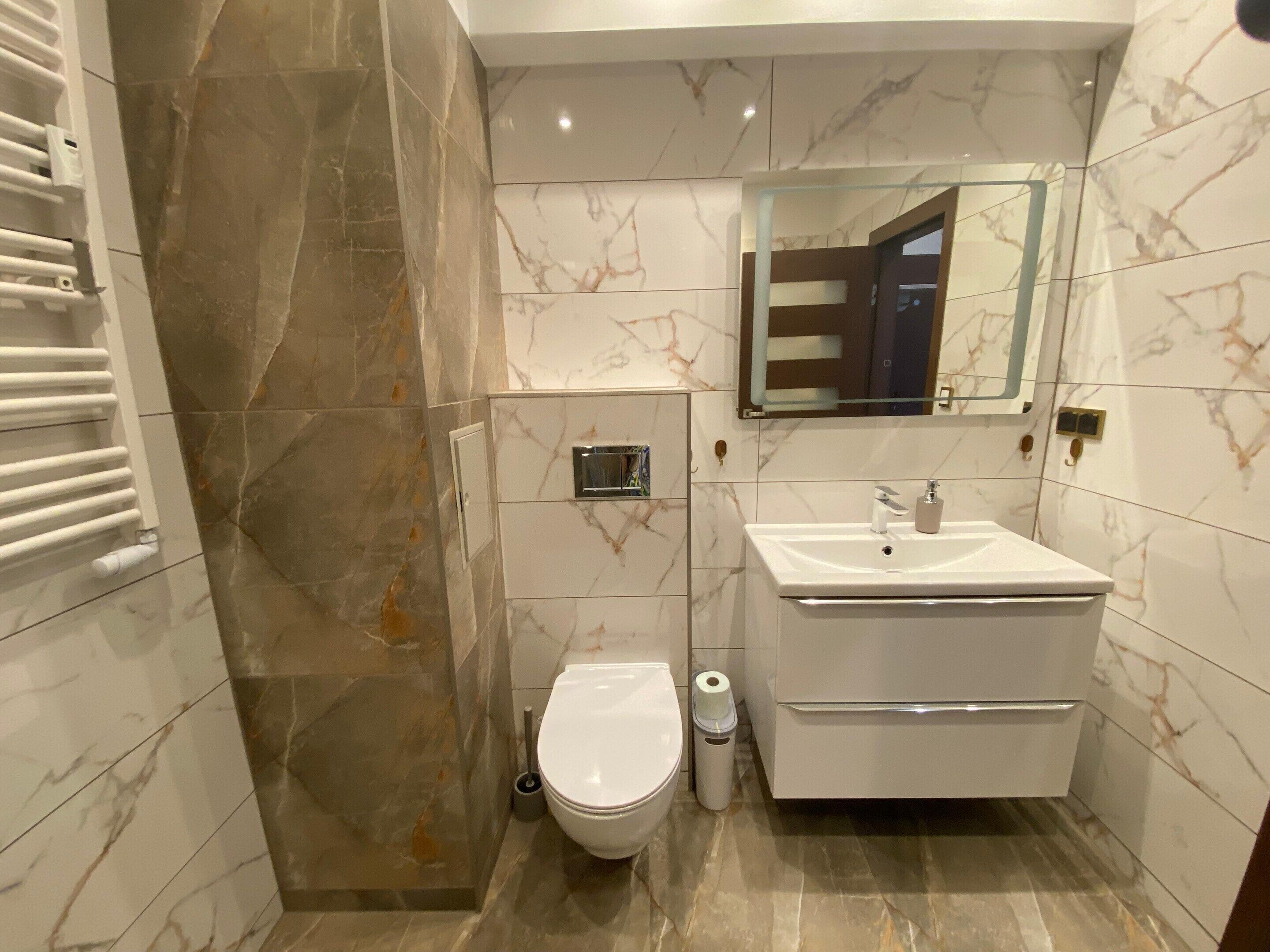 Un baño moderno con un inodoro blanco, un lavabo y un espejo encima.