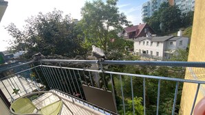A balcony with metal railings, a chair, and a view of buildings and trees. - Apartment Close to the Beach, Miedzyzdroje (Międzyzdroje)