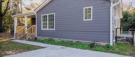 A single-story house with a front porch, a small staircase, and a stone foundation.