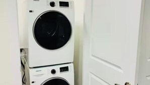 A laundry room with two stacked washing machines and two bottles of detergent on top. - Stylish One Bedroom Cozy Home (Edmonton)