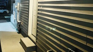 A house exterior at night with horizontal siding, a visible garage door, and a small porch area with steps. - Stylish One Bedroom Cozy Home (Edmonton)