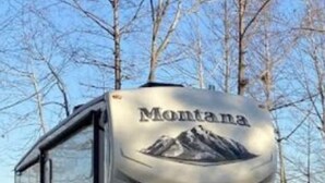 Una caravana Montana con un gráfico de montaña en la parte trasera, una puerta corredera y una plataforma plana.