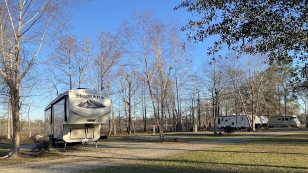 Una caravana estacionada en un camping, con árboles y otras caravanas al fondo.