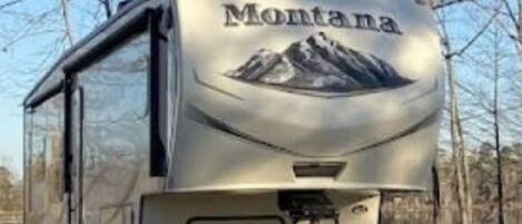 A Montana RV with a mountain graphic on the back, a sliding door, and a flatbed.