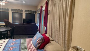 A bedroom with a bed, a desk, a sofa, and a TV.