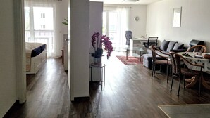 A spacious living area with a dining table, chairs, a sofa, and a small desk.