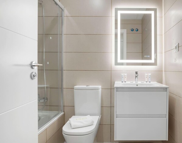 Un baño moderno con cabina de ducha de vidrio, inodoro blanco y tocador con espejo.