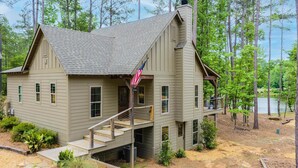 A two-story house with a balcony, a chimney, and an American flag. - Firefly Cottage, Firefly Cottage | Lake Martin Getaway | Sleeps 8 | Pet Friendly (Elmore County)