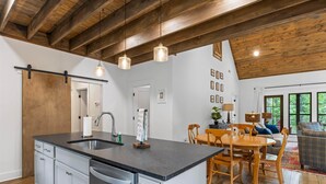 A kitchen with a central island, wooden ceiling beams, and pendant lighting. - Firefly Cottage, Firefly Cottage | Lake Martin Getaway | Sleeps 8 | Pet Friendly (Elmore County)