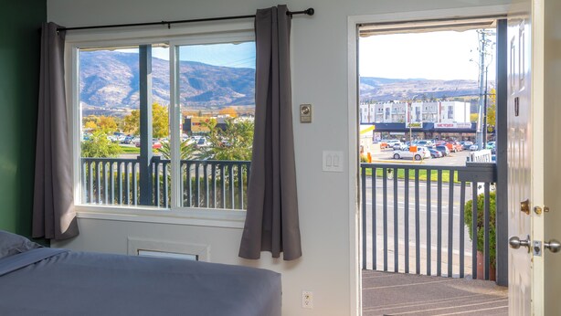 Une chambre d’hôtel avec une grande fenêtre, un lit et une vue sur un parking et des immeubles.