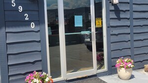Un bâtiment avec une enseigne indiquant « BUREAU » au-dessus de l’entrée, une boîte aux lettres et deux jardinières sur le trottoir.