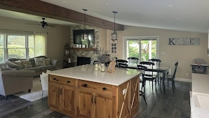A spacious kitchen with a central island, a dining area with black chairs, and a cozy seating area with a sofa.
