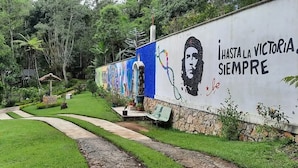 A garden pathway leading to a building with a mural and the text "I HASTA LA VICTORIA SIEMPRE". - Eco Hotel Villa Canaan (Cobán)