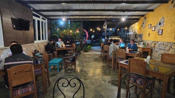 A restaurant with outdoor seating, stone walls, and a TV mounted on the wall. - Eco Hotel Villa Canaan (Cobán)