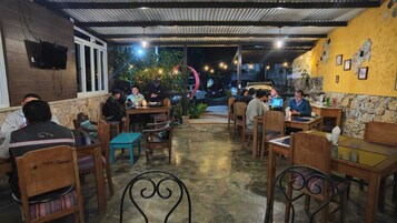 Un restaurante con mesas al aire libre, paredes de piedra y un televisor montado.