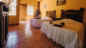 A room with two beds, a fireplace, and a window with curtains. - Eco Hotel Villa Canaan (Cobán)