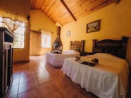 Una habitación con dos camas, una chimenea y un ventanal con cortinas.