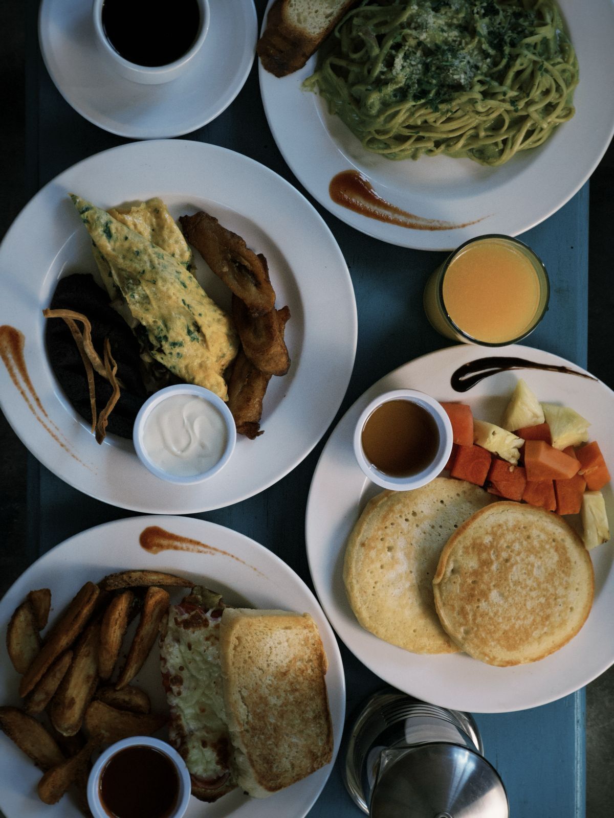 A breakfast spread with various dishes including pancakes, French toast, omelette, and hash browns.