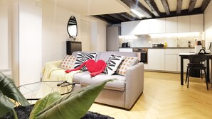 Ein modernes Wohnzimmer mit Sofa, Essbereich und einer Küche im Hintergrund.