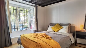 Ein Schlafzimmer mit Bett, Fenster, Nachttisch und Lampe.