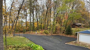 A paved driveway leading to a garage, surrounded by trees with autumn foliage.