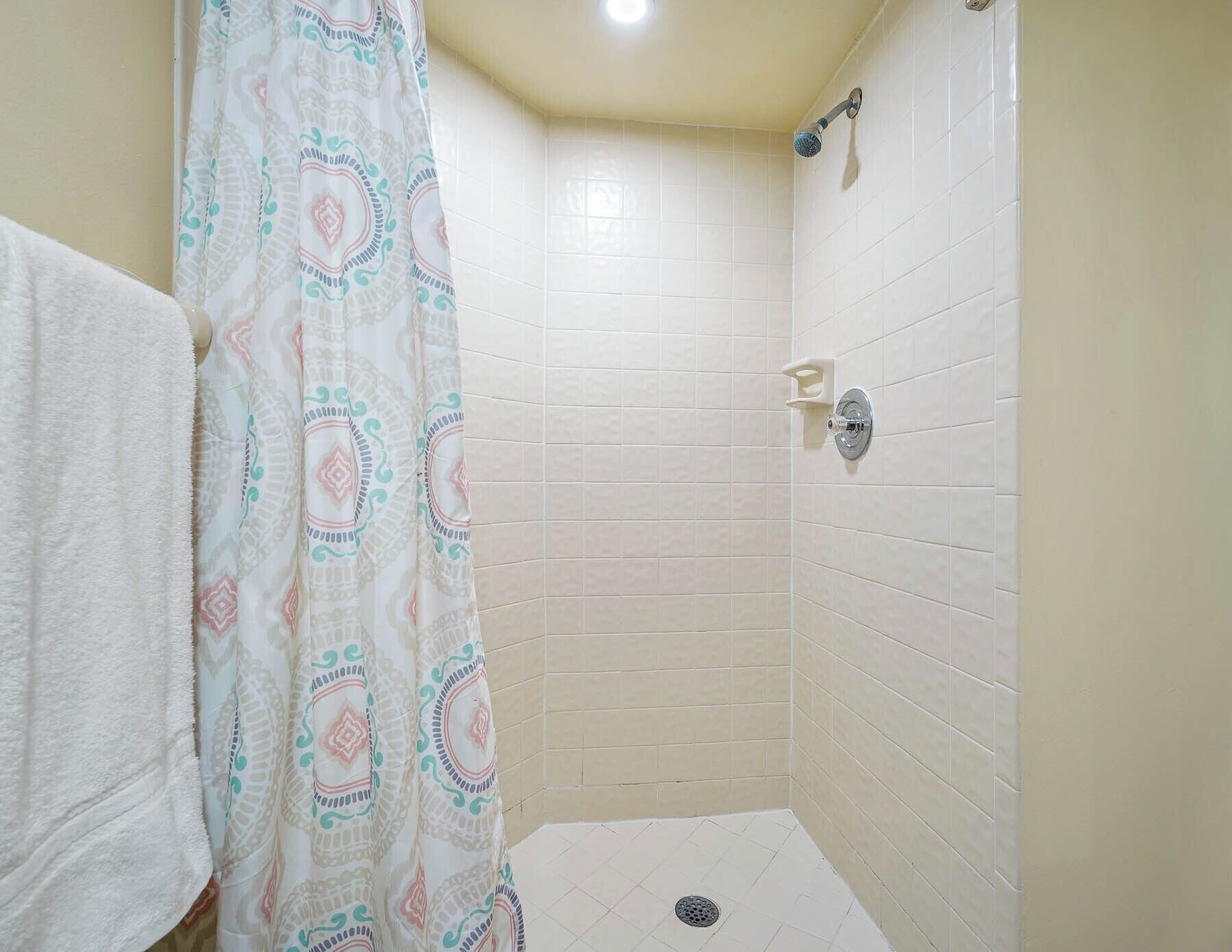 Um pequeno banheiro revestido com azulejos, com chuveiro e ralo.
