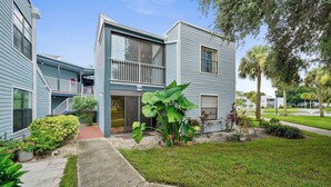 A two-story residential building with a balcony, a small front yard with plants, and a clear sky. - Vacational Apartment at Orlando 3608 (Orlando)