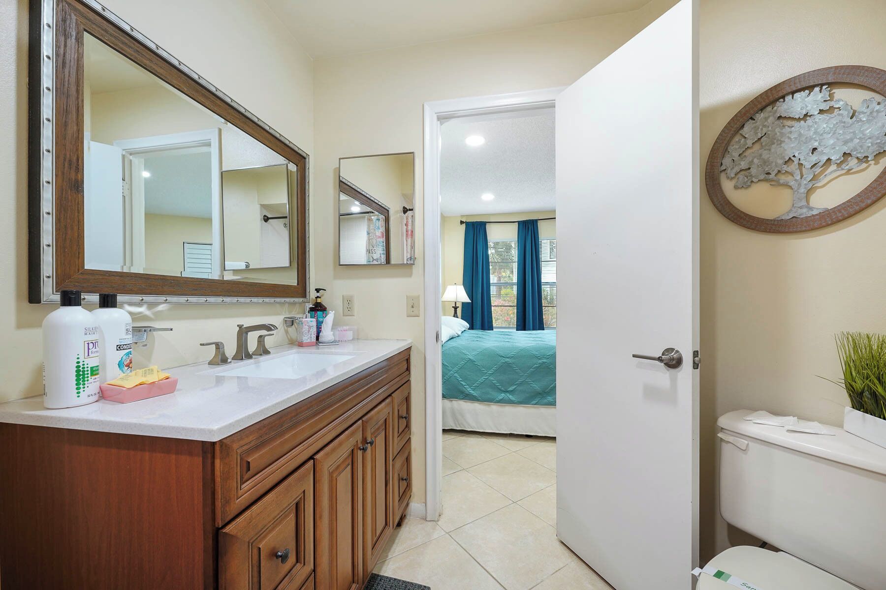 A bathroom with a wooden vanity, a large mirror, and a toilet.