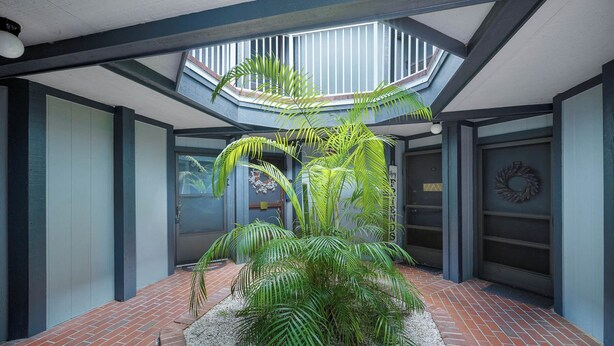 A modern building with a central atrium featuring a large potted plant arrangement. - Vacational Apartment at Orlando 3608 (Orlando)