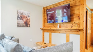 Un salon avec un téléviseur fixé au mur, un meuble en bois et un tableau représentant un taureau.