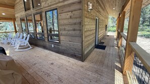 Una cabaña de madera con ventanas amplias, un porche cubierto y mecedoras.