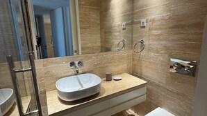 Un baño moderno con cabina de ducha de vidrio, un lavabo blanco y un inodoro.