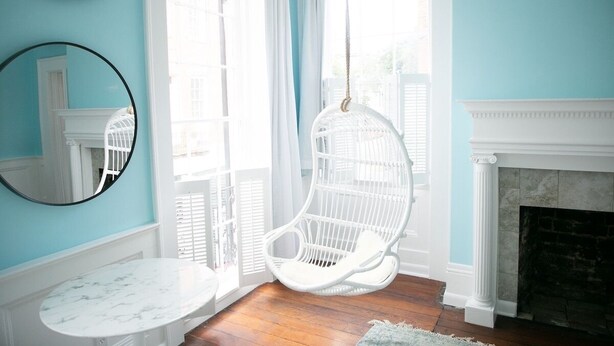 A room with a hanging chair, a marble table, and a fireplace.