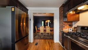 Una cocina con armarios de madera oscura, electrodomésticos de acero inoxidable y una pared de ladrillo decorativa.