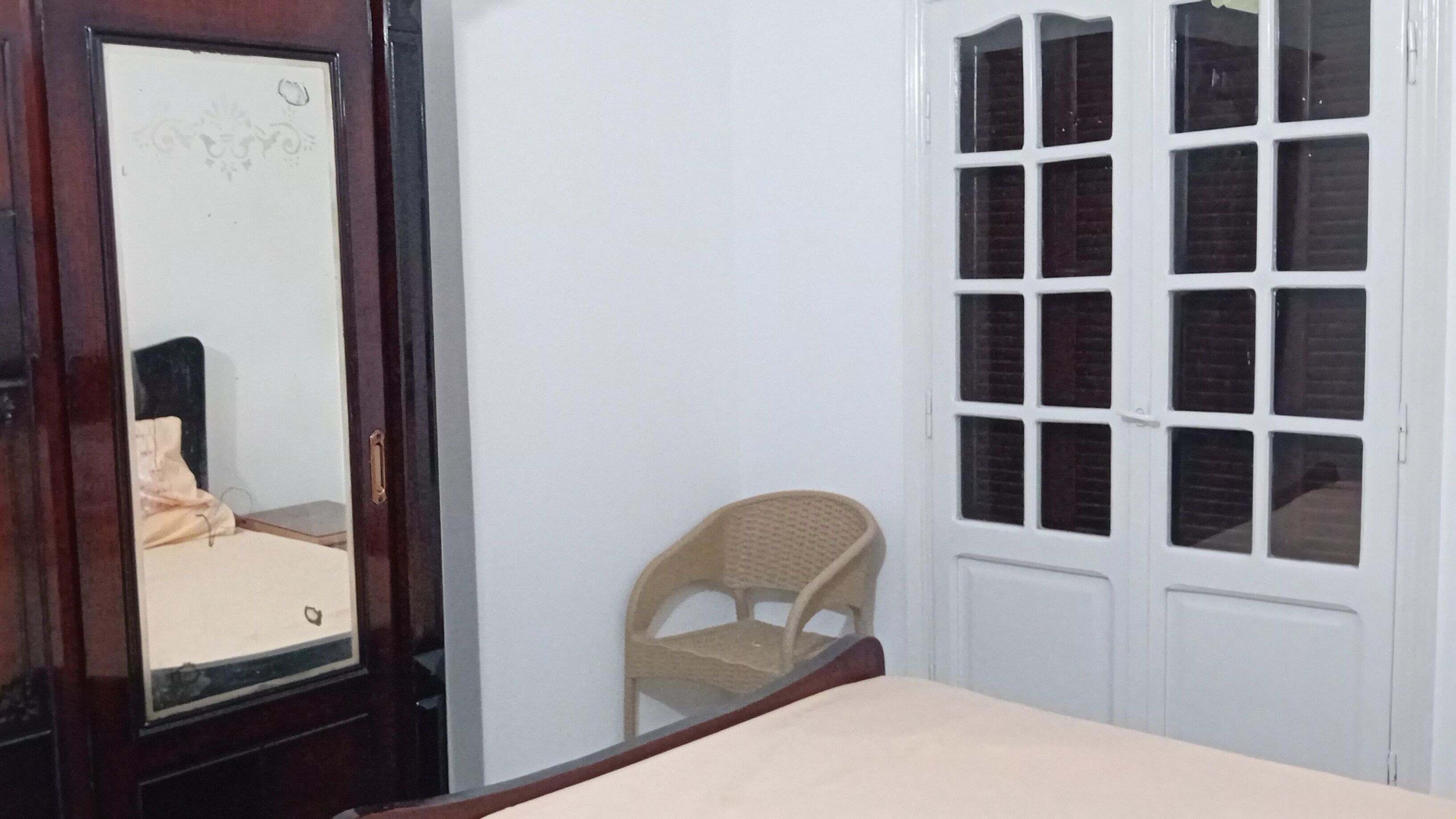 Une pièce comprenant un lit, une chaise, une armoire et une fenêtre à carreaux.