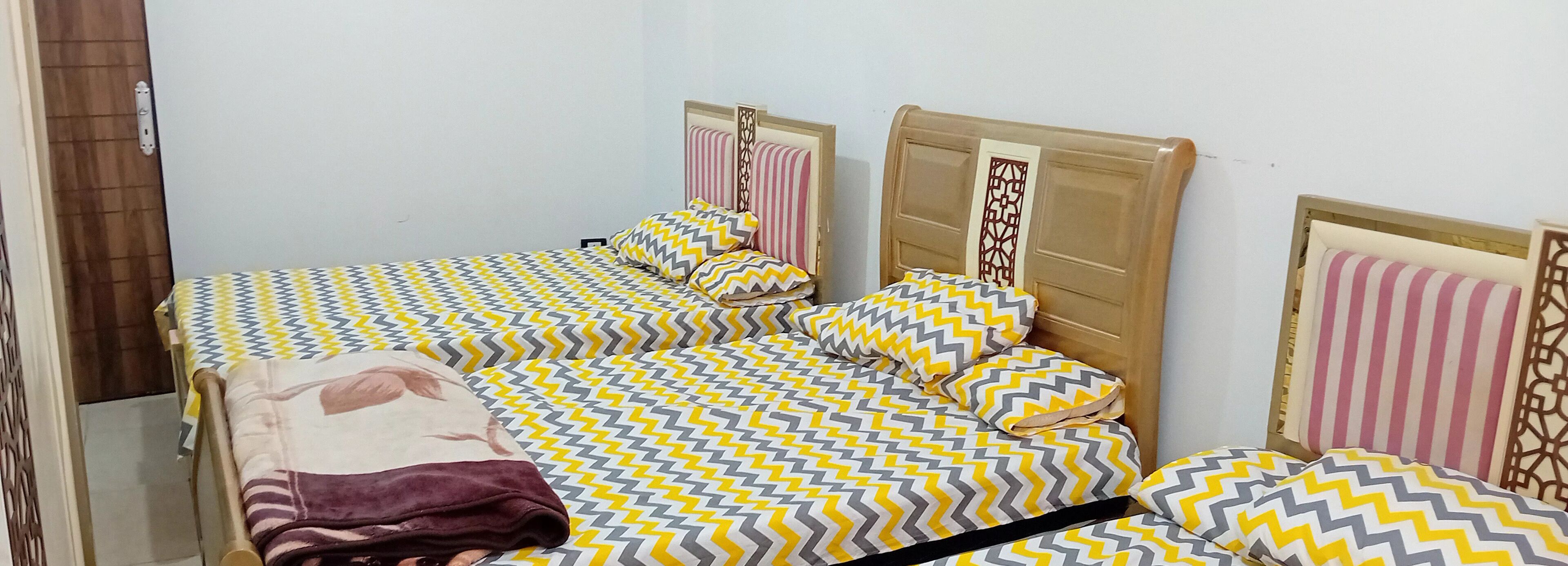 A room with two beds, each with patterned bedding and headboards.