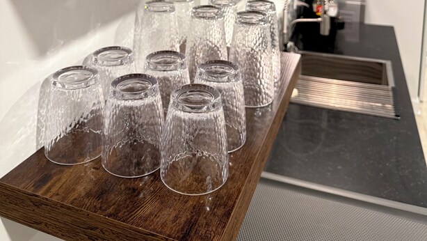 A wooden shelf with a patterned pot and glassware.