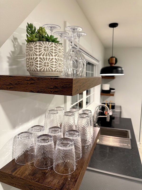 Une étagère en bois avec un pot décoré et des objets en verre.