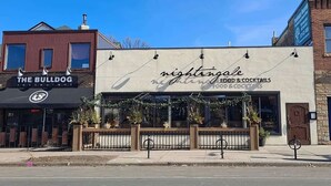 Un restaurante llamado 'Nightingale' con terraza y un cartel de 'The Bulldog' al otro lado de la calle.
