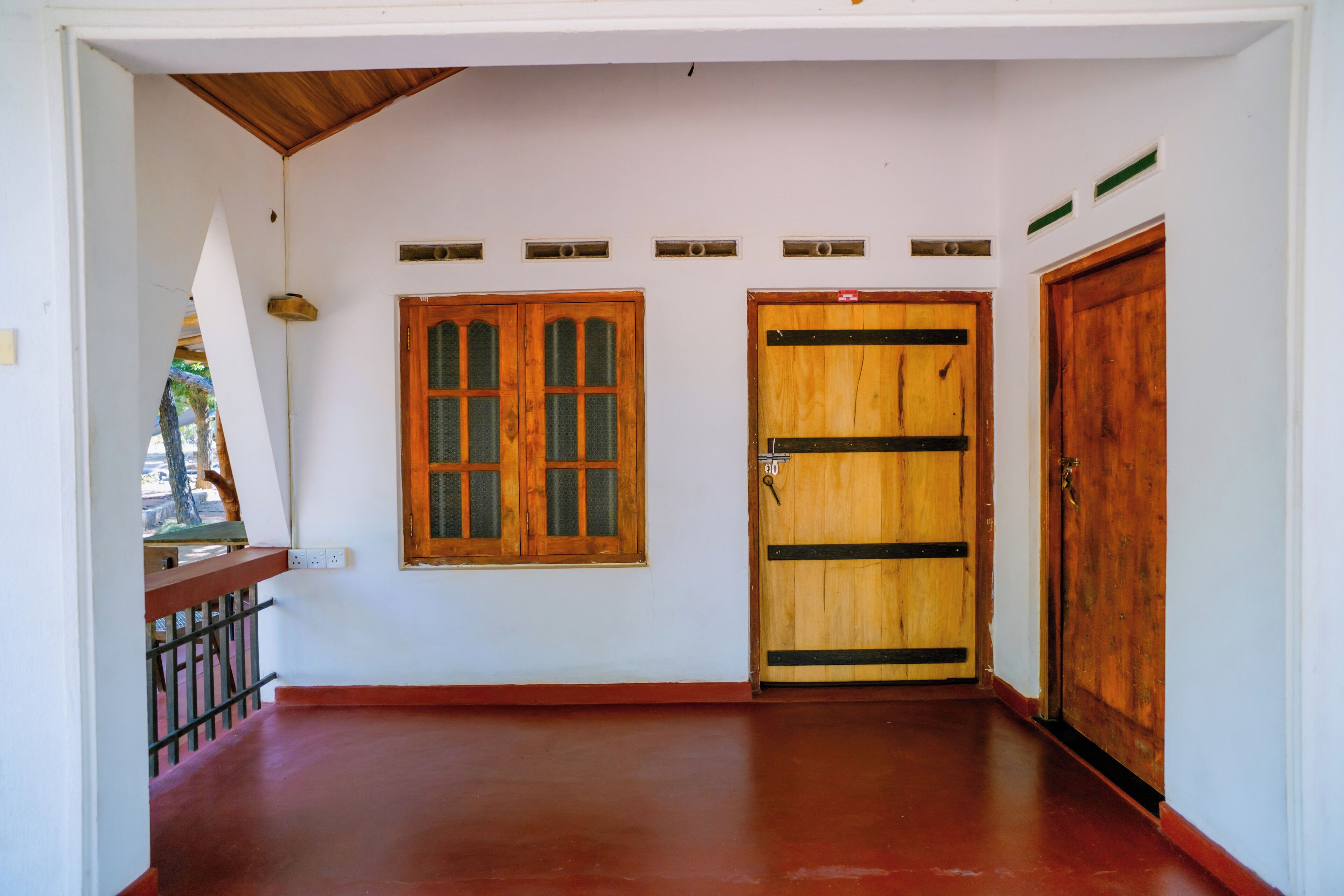 Un couloir avec une porte en bois, une fenêtre et un escalier.