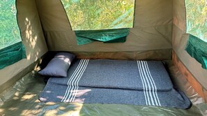 Tienda de campaña con zona de descanso, que incluye una cama y una almohada.