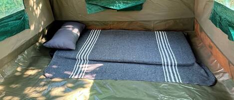A tent with a sleeping area, including a bed and a pillow.