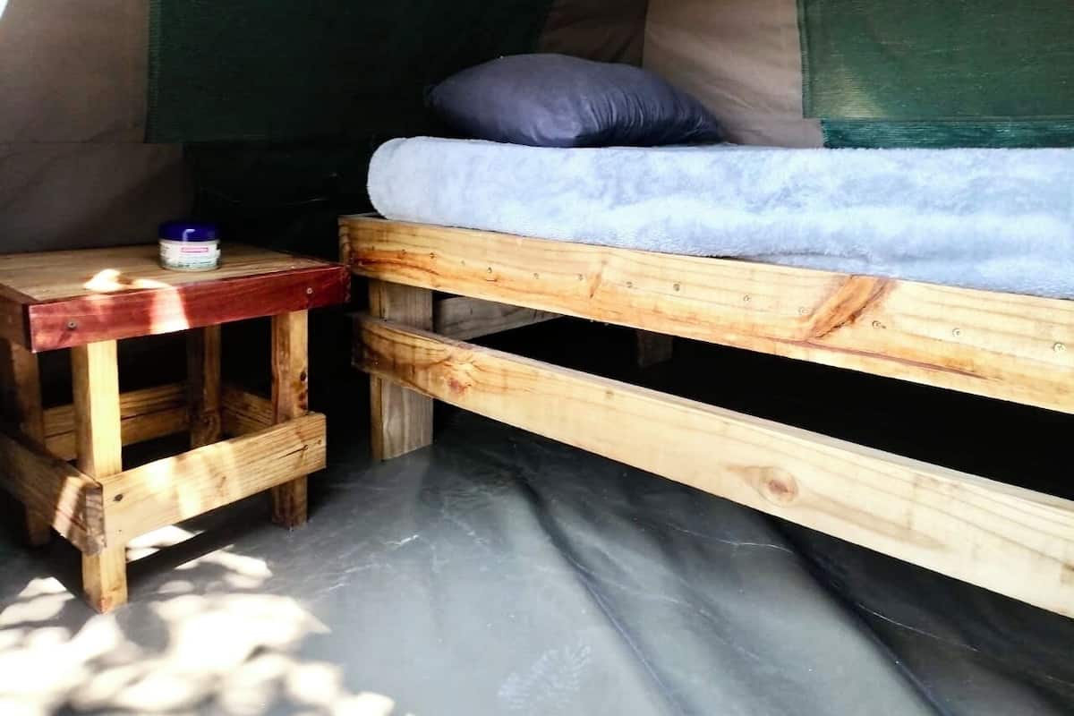 Ein Zelt mit einem hölzernen Bett und einem kleinen Holztisch.