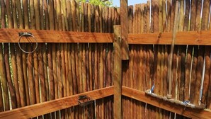 Una cerca de madera con un portón de metal y un anillo metálico.