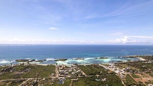 Vista aérea de uma área costeira com um porto de iates, edifícios e águas azul-claras.