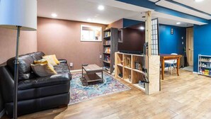 Una sala de estar moderna con un sofá de cuero negro, una mesa de centro, un mueble para televisión y una estantería.